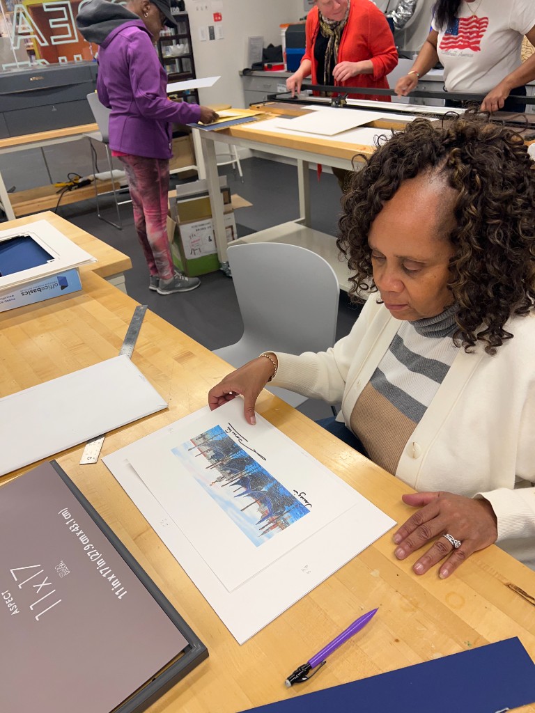 Workshop participants framing art at a studio table