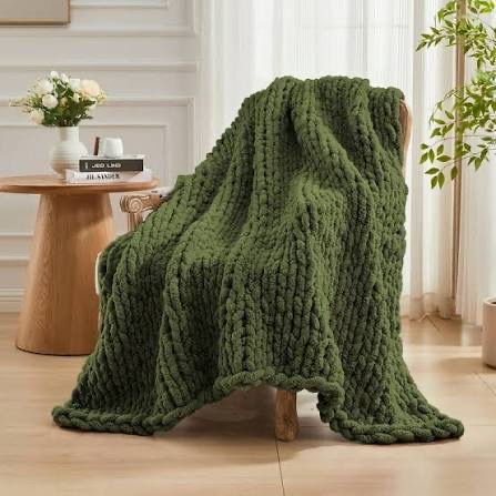 Sage green chunky knit blanket draped over a wooden armchair