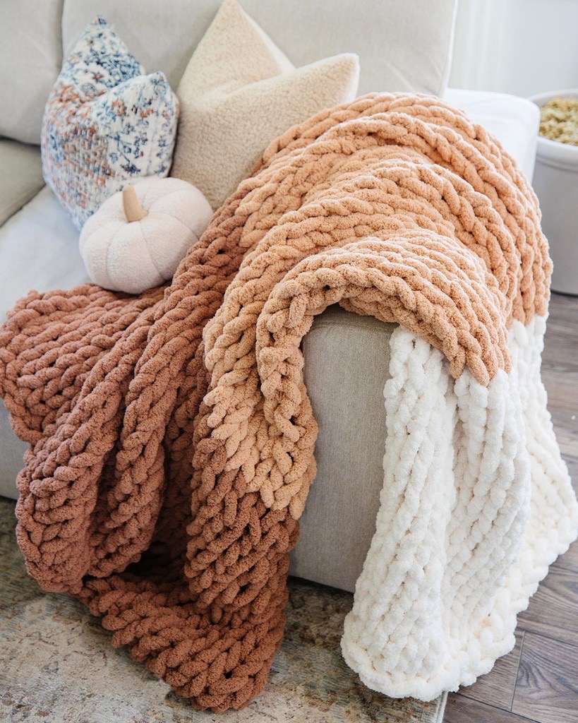 Terracotta, tan, and cream color-blocked chunky knit blanket on a sofa