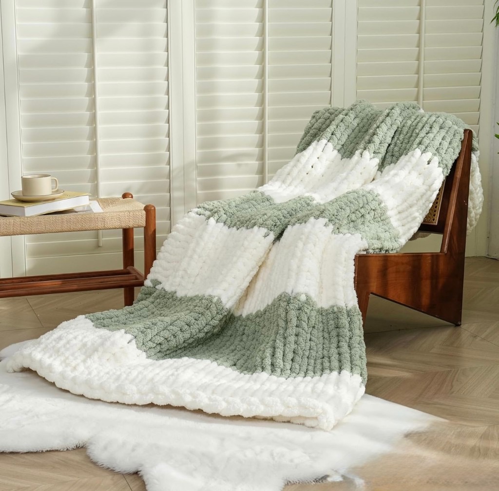 Sage green and cream striped chunky knit blanket on a mid-century chair