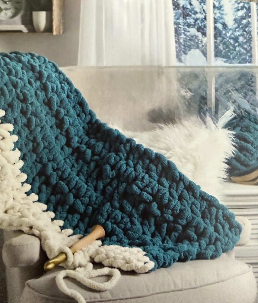 Teal chunky knit blanket in progress with a wooden crochet hook