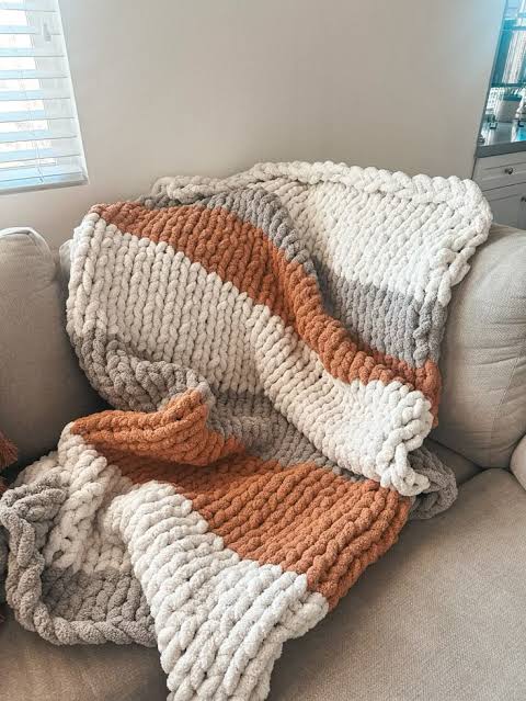 Rust, cream, and gray color-blocked chunky knit blanket on a sofa