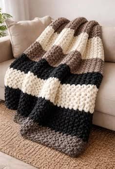 Black, cream, and brown striped chunky knit blanket on a sofa