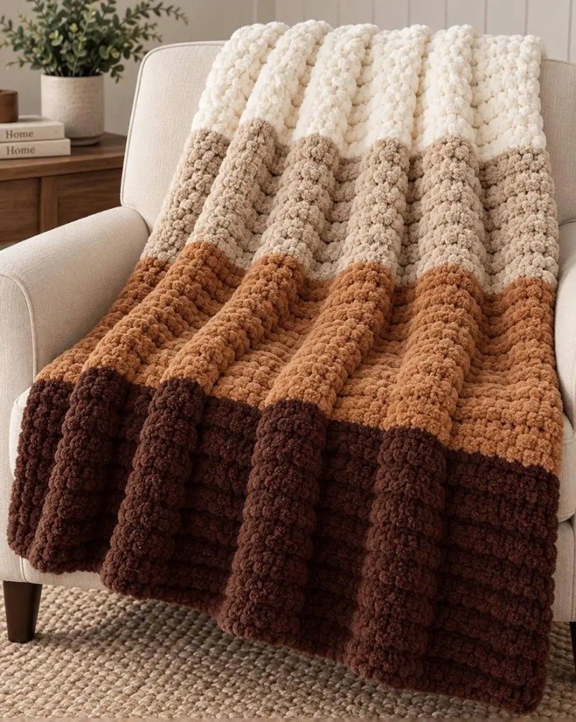 Cream, tan, and brown ombre chunky knit blanket on an armchair