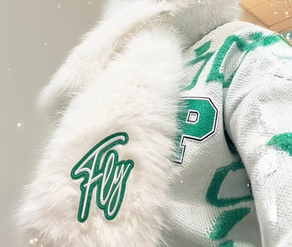 Close-up of a white faux-fur jacket with green Fly and varsity P patches