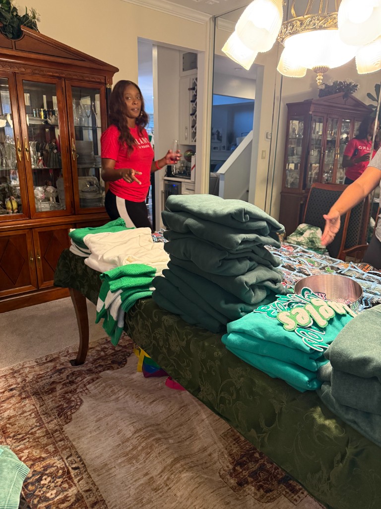 Stacks of green and white sweatshirts laid out on a table before the event