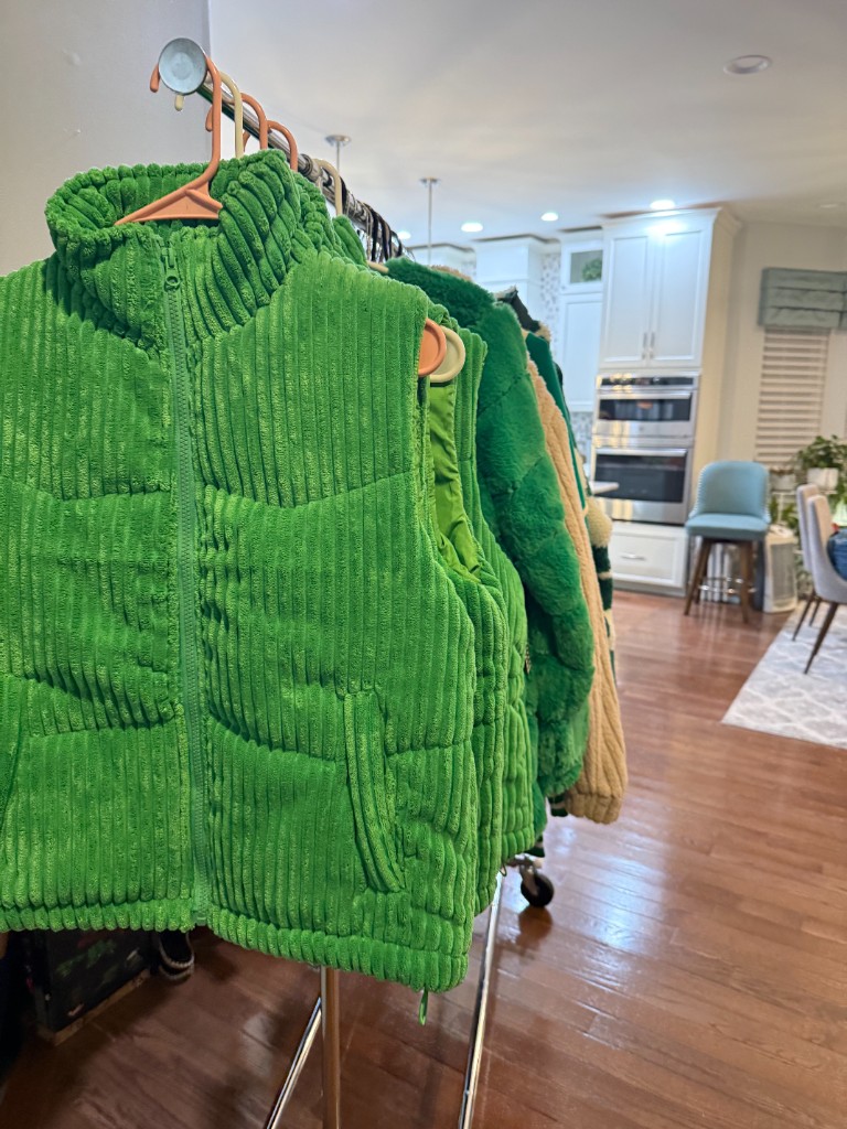 A rack of green corduroy vests and faux-fur coats ready for custom patches