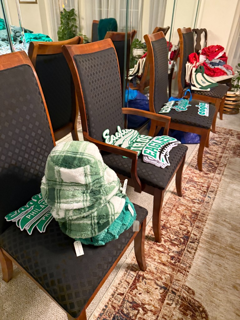 Eagles patches and a plaid hat arranged on dining chairs