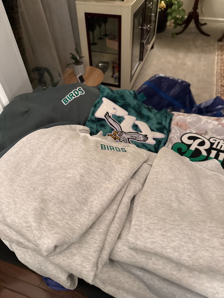 Folded sweatshirts with Birds and eagle patches piled together
