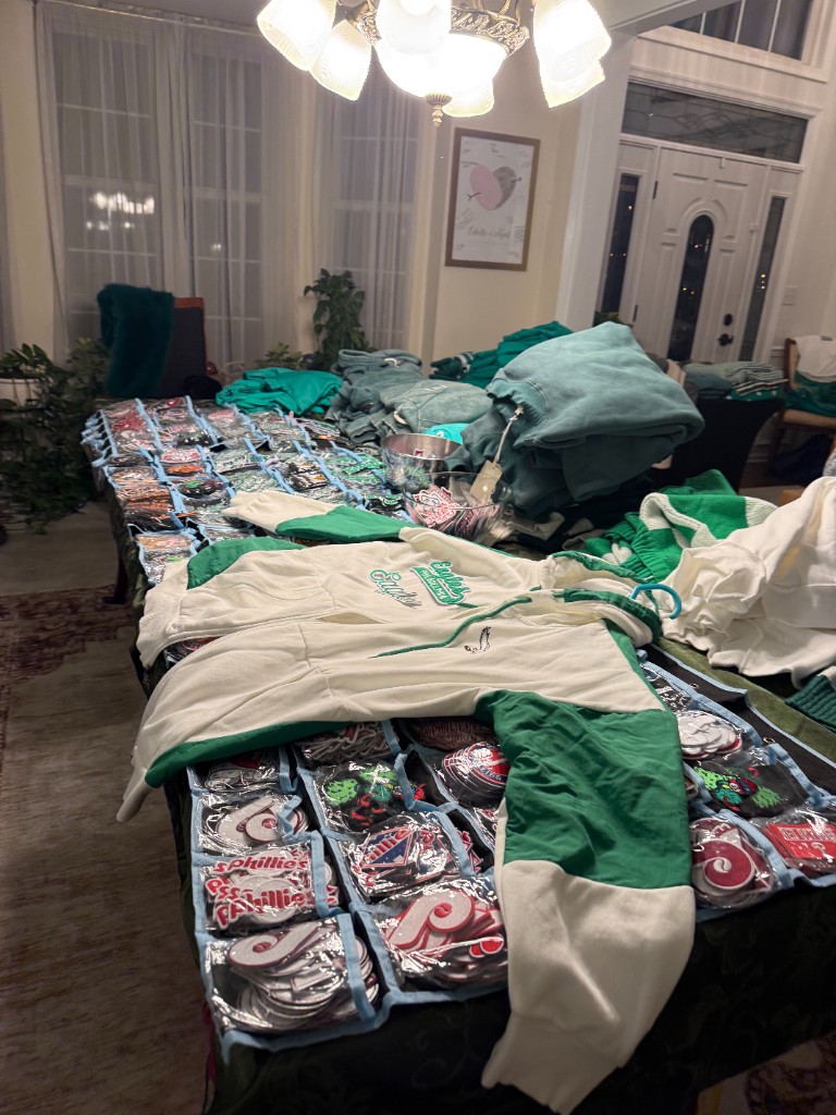 A table covered with a patch organizer, folded apparel, and a white and green Eagles hoodie