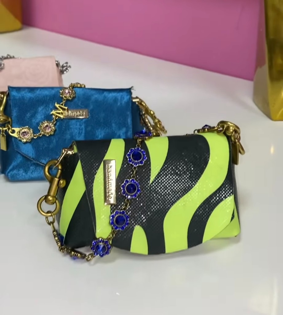A neon zebra handmade purse beside a blue velvet purse